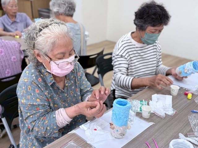 長輩們正在專心將貝殼與珍珠裝飾於花瓶。 長輩們正在專心將貝殼與珍珠裝飾於花瓶。